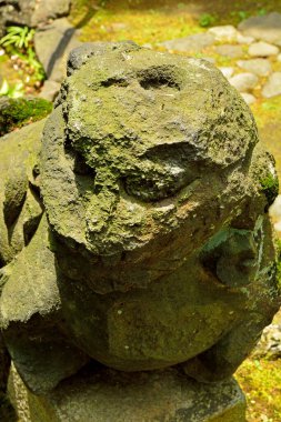 Eski heykelin yıpranmış yüzeyi, Japon yazının parlak ışığına güzel bir tezat oluşturuyor..