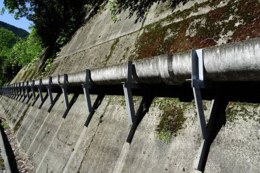 Dışarıdaki beton istinat duvarı boyunca uzanan büyük metal boru.