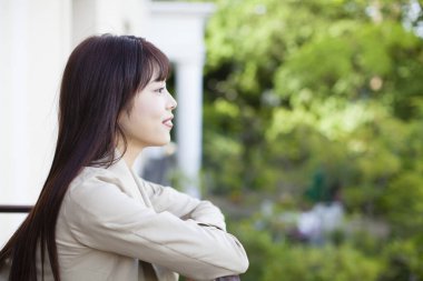 Balkonda uzun saçlı Asyalı bir kadının portresi.