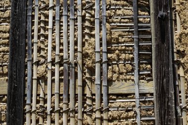 Weathered wooden beams supporting textured mud wall