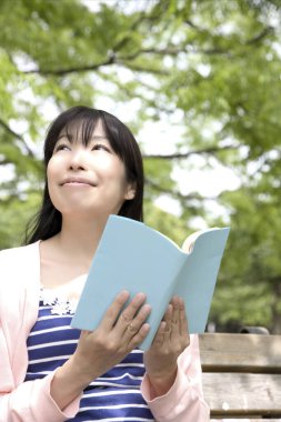 Genç Japon kadın Green Park 'ta kitap okuyor. 