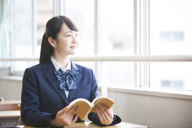 Üniformalı, kitap okuyan Asyalı bir kızın portresi.