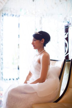 Güzel genç gelinin portresi içeride oturuyor ve yan bakıyor. 