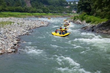 İnsanlar Rapid Mountain nehrinde rafting yapıyor, rafting yapıyorlar.                 