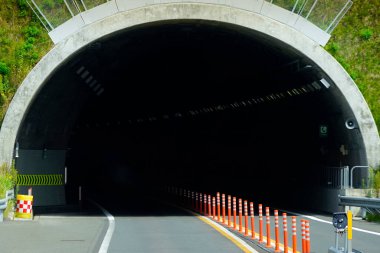Turuncu trafik konileriyle çevrili karanlık tünel girişi.