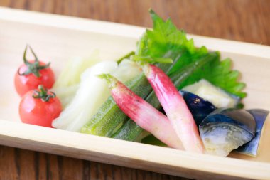 Fresh vegetables and fish arranged neatly on wooden tray
