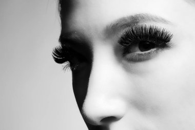 Uzun kirpikleri olan güzel bir kadın yüzü. güzellik ve moda konsepti. Yakın plan, genç bir kadının portresi. siyah beyaz fotoğraf 