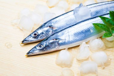 Yeşil yapraklı çiğ uskumru balığı ve ahşap zemin üzerinde buz küpleri