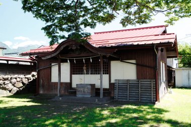 Yeşil ağaçlar ve çimlerle çevrili geleneksel ahşap bina