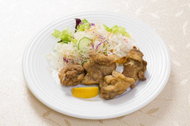 Kızarmış tavuk parçaları ve beyaz tabakta sebze salatası.