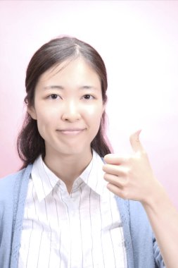 Genç Asyalı kadın baş parmağını gösteriyor.