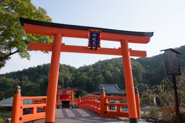 Geleneksel tahta köprünün yanında duran büyük kırmızı torii kapısı.