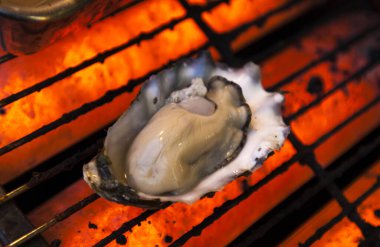 Sıcak turuncu ızgarada taze istiridye ızgarası.