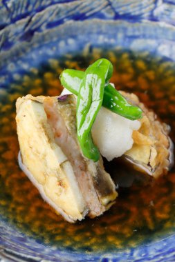 Japanese dish featuring fried fish garnished with green pepper