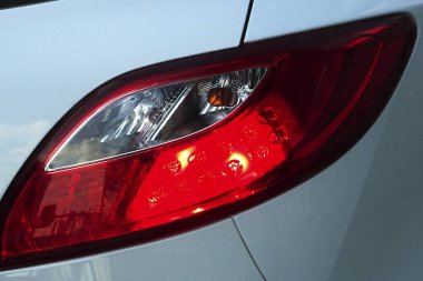 Yakından bakınca kırmızı arabanın arka lambası gümüş araçtaki güneş ışığını yansıtıyor.