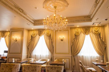 Süslü avize ve lüks perdelerin olduğu zarif yemek odası.