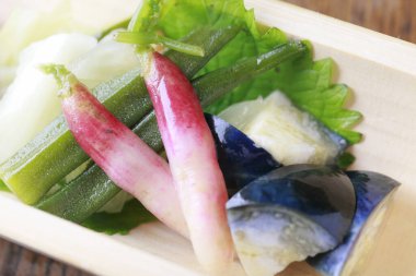 Fresh pickled vegetables resting atop green leafy garnish