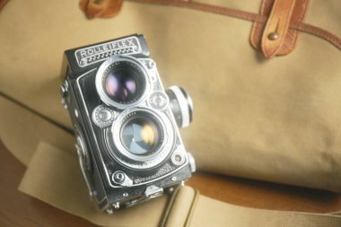 Kahverengi deri çantanın önünde eski çift lensli kamera Rolleiflex
