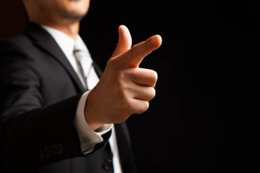 Takım elbiseli işadamı siyah arkaplanda işaret işareti gösteriyor