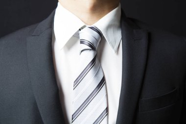 Koyu arkaplanda takım elbise giyen ve kravat takan işadamı görüntüsü