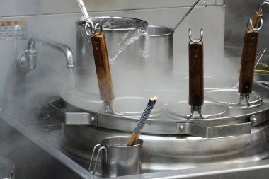 Buharlı metal erişte sepetleri ticari mutfak malzemelerinin içinde duruyor.