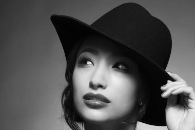 Stüdyoda siyah beyaz şapka takan güzel Asyalı kadının portresi.
