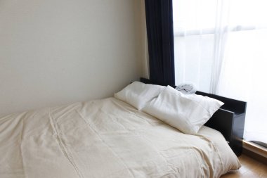 Beyaz yatak, yastıklar ve oda içi battaniye.