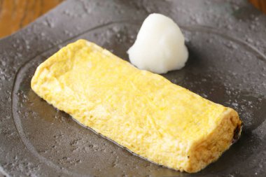 Japanese tamagoyaki omelette resting beside grated daikon radish
