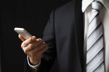 Siyah arka plan üzerine Smartphone kullanarak iş adamı