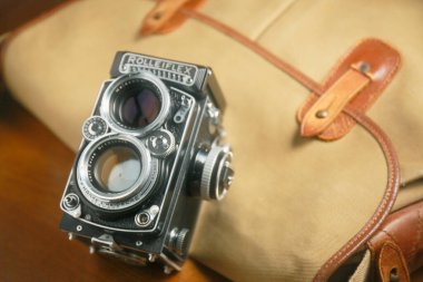 Kahverengi deri çantanın önünde eski çift lensli kamera Rolleiflex