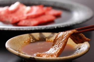 Dipping meat slice into sauce
