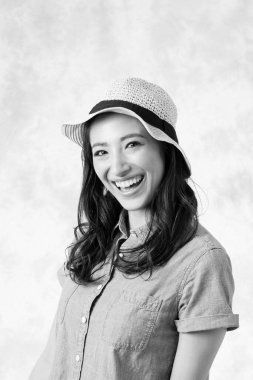 Hasır şapkalı genç Asyalı kadın, gülümsüyor.