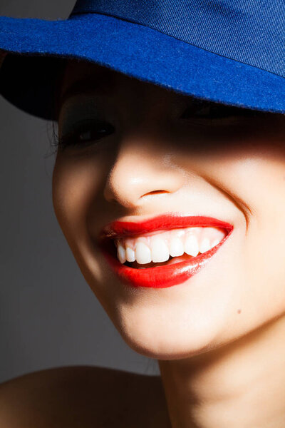 portrait of a beautiful young woman with blue lipstick and hat on her face.