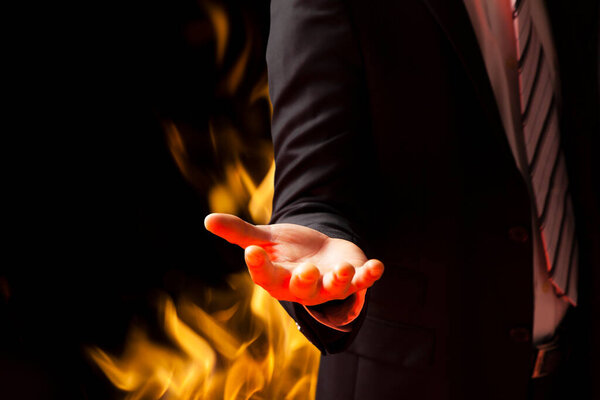 Businessman in suit holding flame over black background