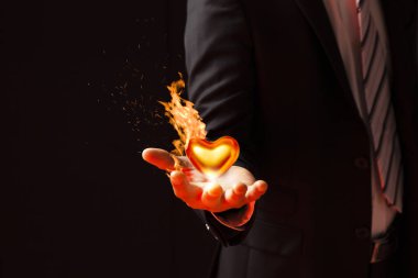 Takım elbiseli bir işadamı siyah arkaplanı ateşe veriyor.