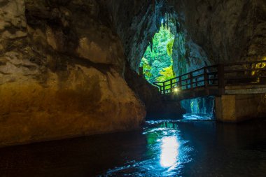 Su üzerinde köprüsü olan dağlarda güzel bir mağara.