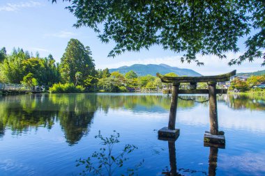 Kinrin Gölü ve Japon kapısı (Torii) Yufu Dağı ve Yufuin, Oita, Kyushu, Japonya 'da mavi gökyüzü arka planı ile