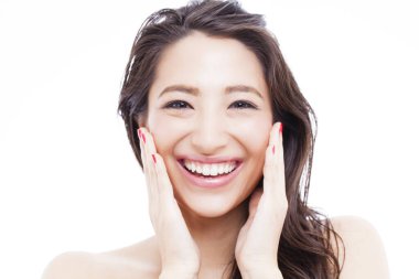 Genç Asyalı kadın yüzüne dokunuyor.