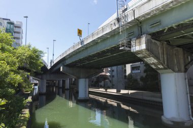 Şehir binaları yakınlarındaki sakin nehri kaplayan beton köprü