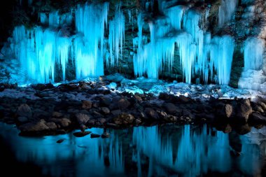 Güzel göl manzarası ve mağaradaki aydınlanmış sarkıtlar.