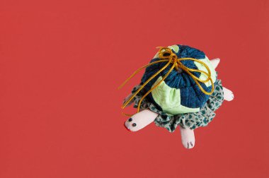 Kırmızı arkaplanda dinlenen renkli el yapımı kumaş kaplumbağa.
