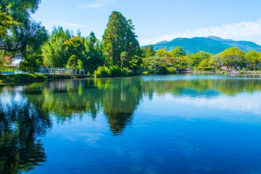 Yufuin, Oita, Kyushu, Japonya 'daki Yufu Dağı ve mavi gökyüzü geçmişi ile Kinrin Gölü.