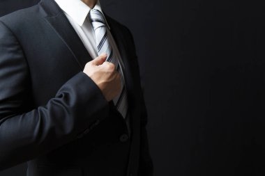 Koyu arkaplanda takım elbise giyen ve kravat takan işadamı görüntüsü