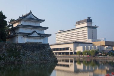 Tarihi Japon kalesi binası modern otel mimarisinin yanında yansıyor.