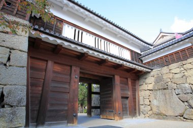 Geleneksel Japon ahşap kapısı büyük taş duvarın yanında duruyor.