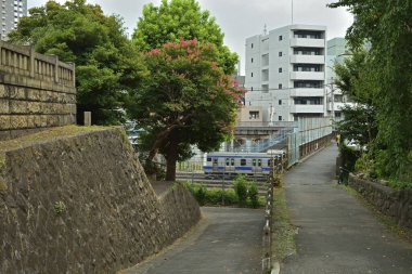 Konut binalarının yanındaki taş duvarın yanında eğimli asfalt yollar.