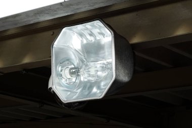 Kapalı çekimde, ahşap çatının altına bağlı açık hava projektörleri görülüyor.