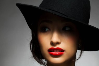 Siyah şapkalı, kırmızı dudaklı güzel Asyalı kadının portresi.