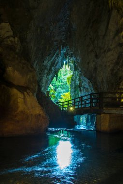 Su üzerinde köprüsü olan dağlarda güzel bir mağara.