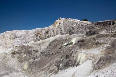 rocky mountain peaks set against bright blue sky, viewed from below